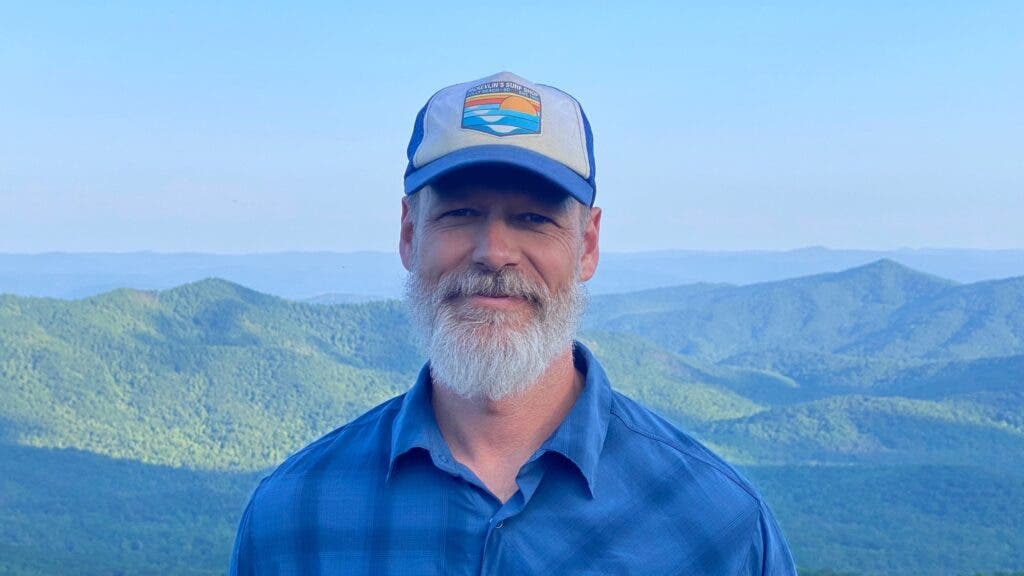 The author wearing a blue flannel and a ball cap, with the green Appalachians in the background