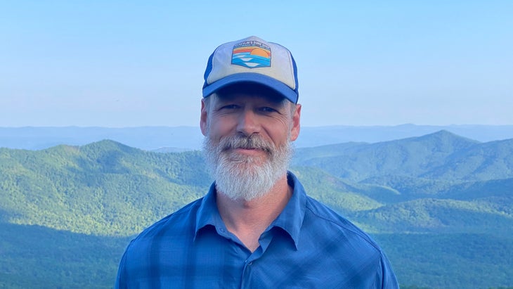 The author wearing a blue flannel and a ball cap, with the green Appalachians in the background
