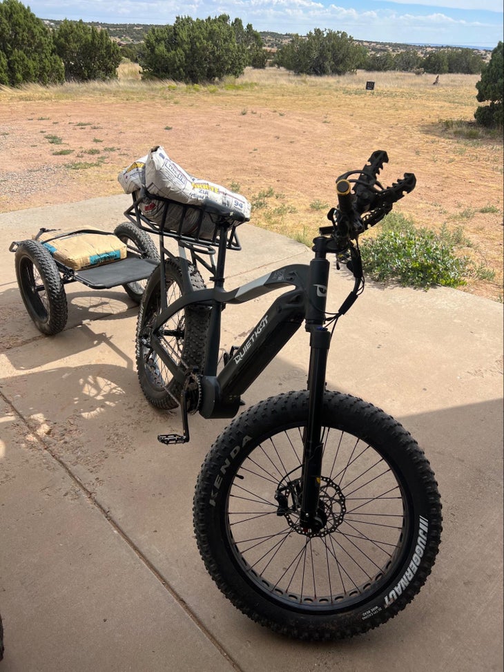 An e-bike loaded with concrete bags on a rack and in a trailer