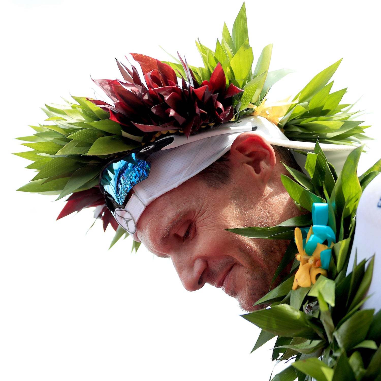 A man with leaves and flowers on his head bows after winning a race
