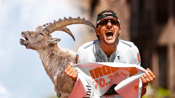 A triathlete finishes a race in a white shirt with a goat behind him.