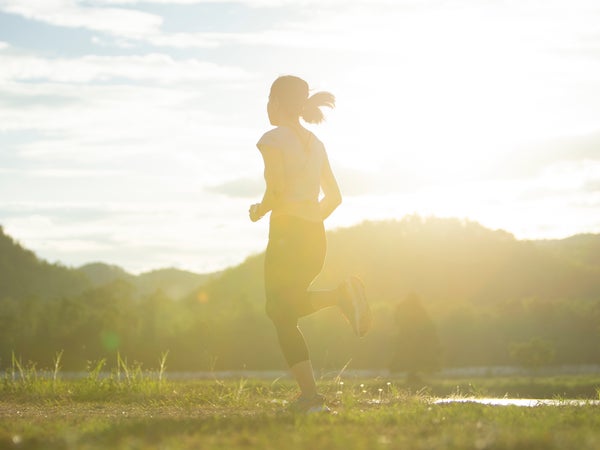 A woman runs on a sun-soaked path