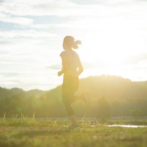 A woman runs on a sun-soaked path