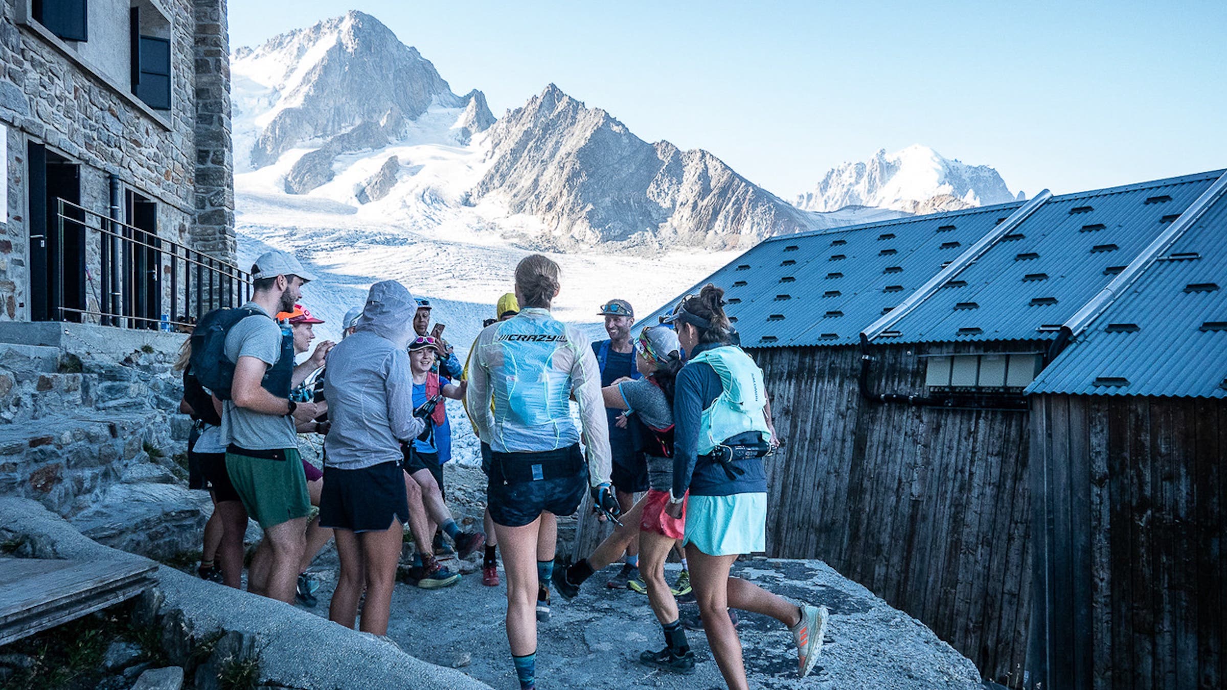 A group of runners gathers at a hut in the mountains