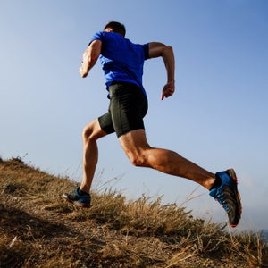 dynamic running uphill on trail male athlete runner side view