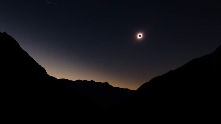 A shot of the total eclipse, with the glowing corona visible, from above a mountain scape in Chile