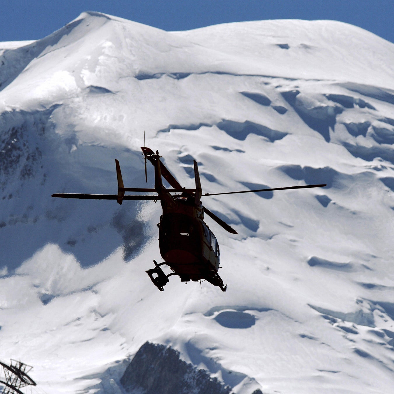 A helicopter flies below the summit of Mont Blanc