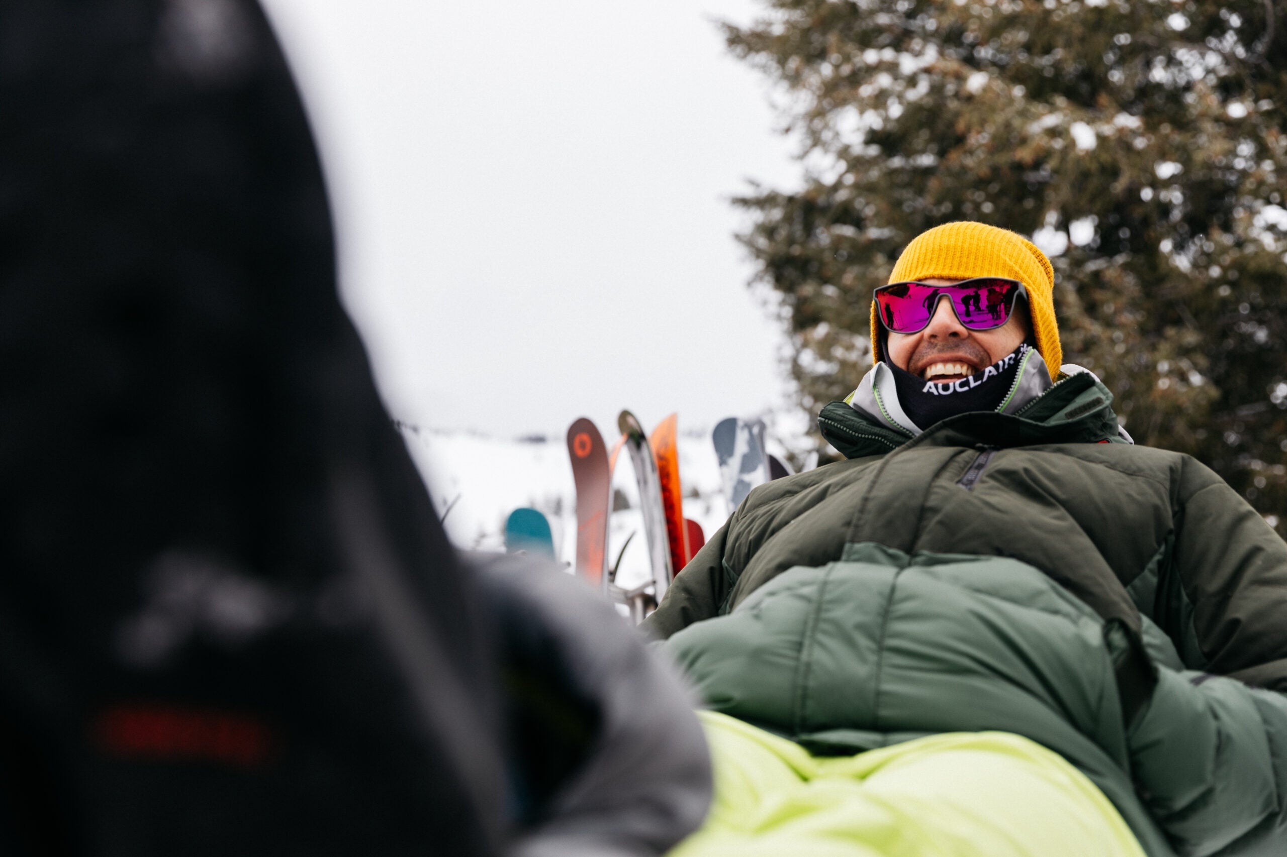 Man wearing ski clothing sitting on chair with feet propped up