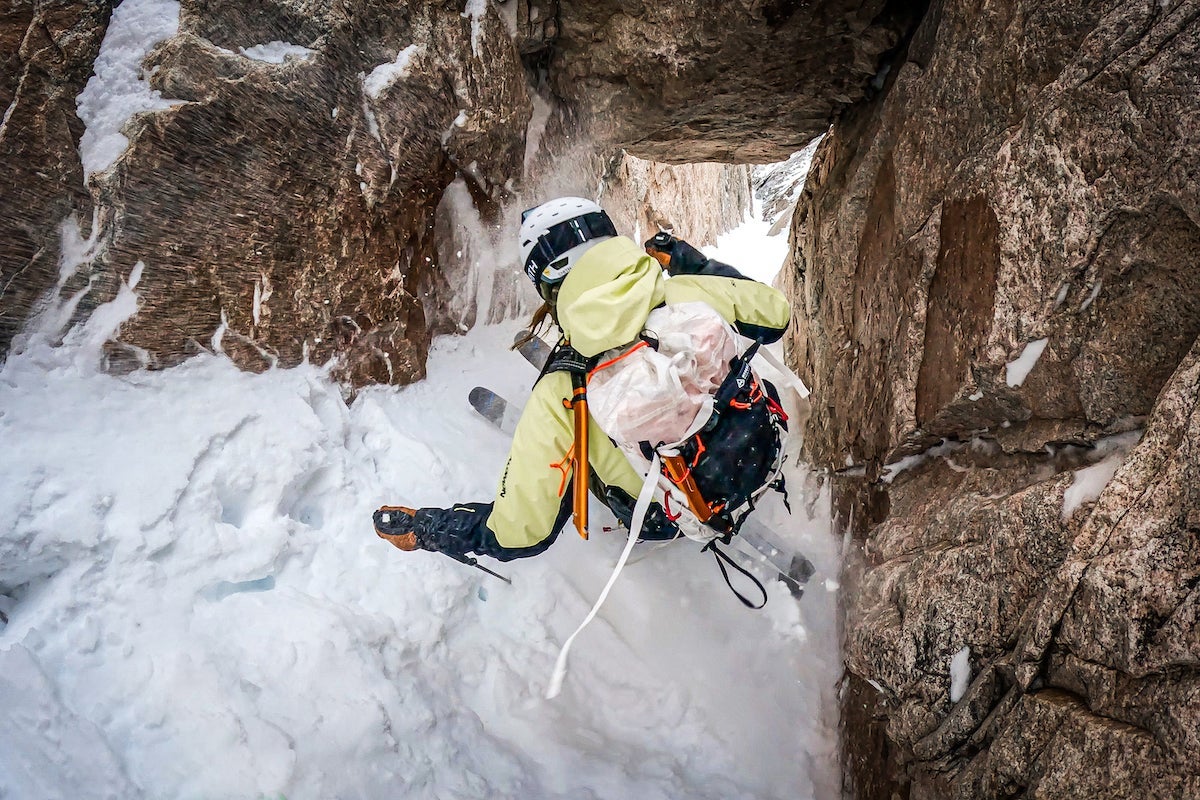 Professional skier Cody Townsend skis down an enclosed couloir wearing a white HMG pack