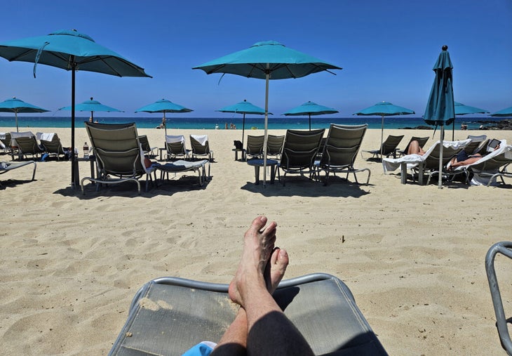 Feet at the beach with umbrellas