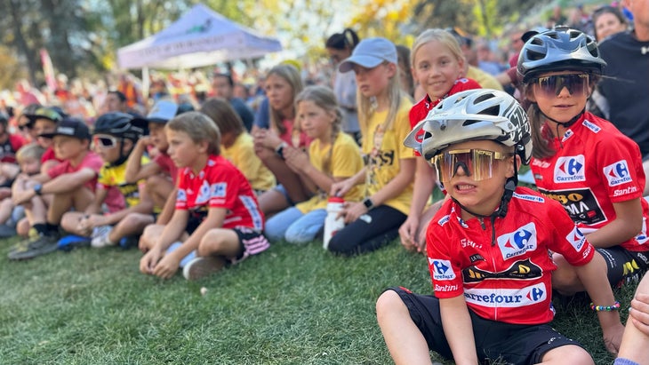 Kids sit in a park in downtown Durango awaiting cyclist Sepp Kuss