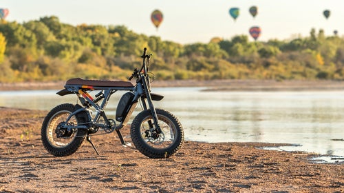 adventure e-bike by river with hot air balloons rising