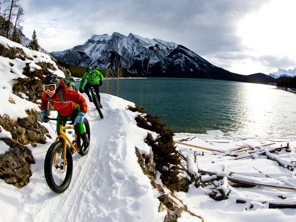 A woman and man enjoy a winter fat bike ride in Banff National Park, Alberta, Canada.
