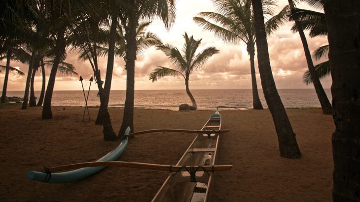 A deserted beach, save for an outrigger boat, in front of Mama's Fish House Restaurant on Maui's North Shore