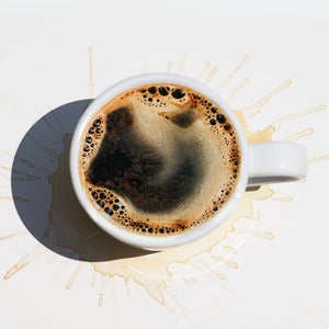 Aromatic morning coffee in a white cup and splash marks from spilled coffee on white color background.