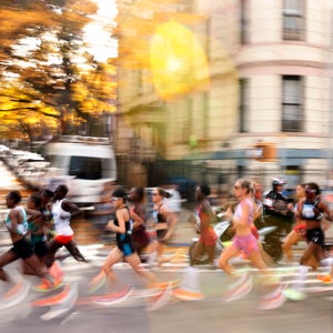 an elite field of women runners runs right to left below and yellow sun