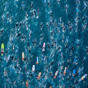An aerial photo of hundreds of swimmers in blue water