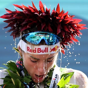 a woman in flower wreaths celebrates winning the ironman