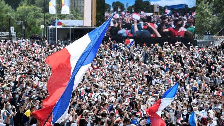 Throngs pack in one of the transmission areas in Paris, with French flags waving and a big-screen TV in the background