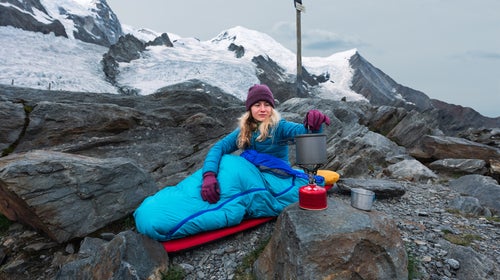 Young woman preparing food outdoors after bivouacking outdoors at La Jonction