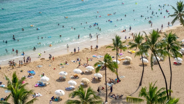 Crowds fill the sands and waters of Waikiki Beach, in Honolulu