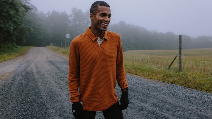 a man wears an orange long sleeve on a misty morning run