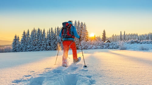 Snowshoe walker running in powder snow with beautiful sunrise light