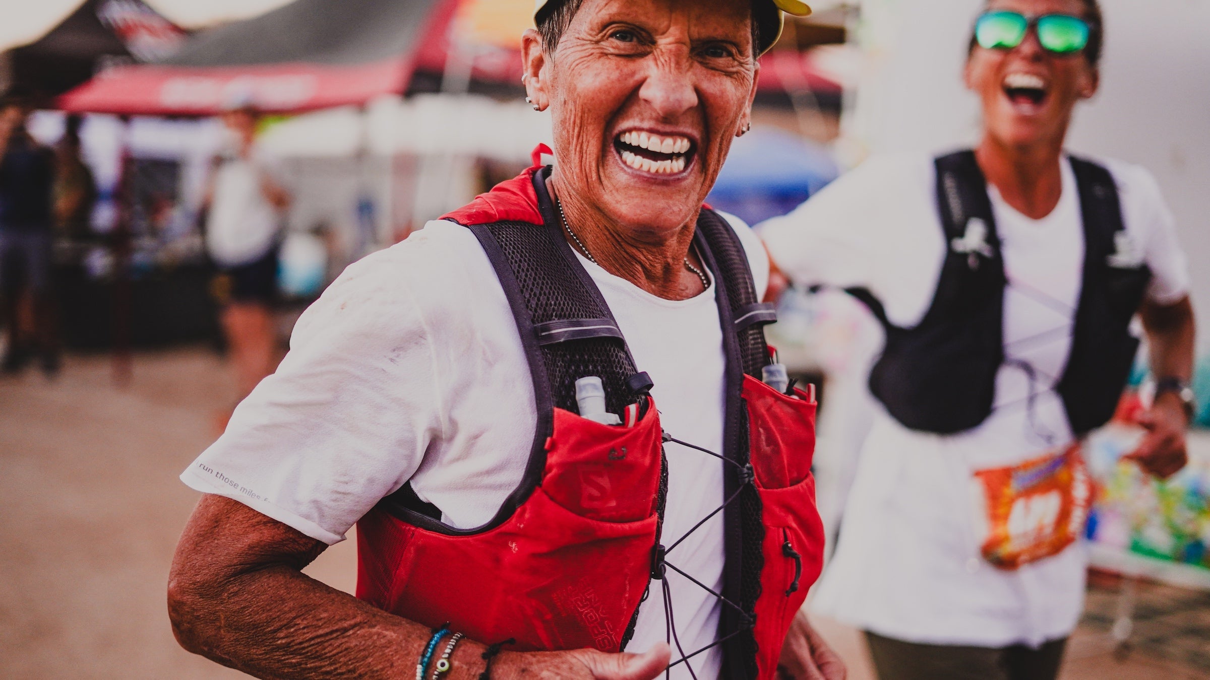 Two women at the race aid station laughing.