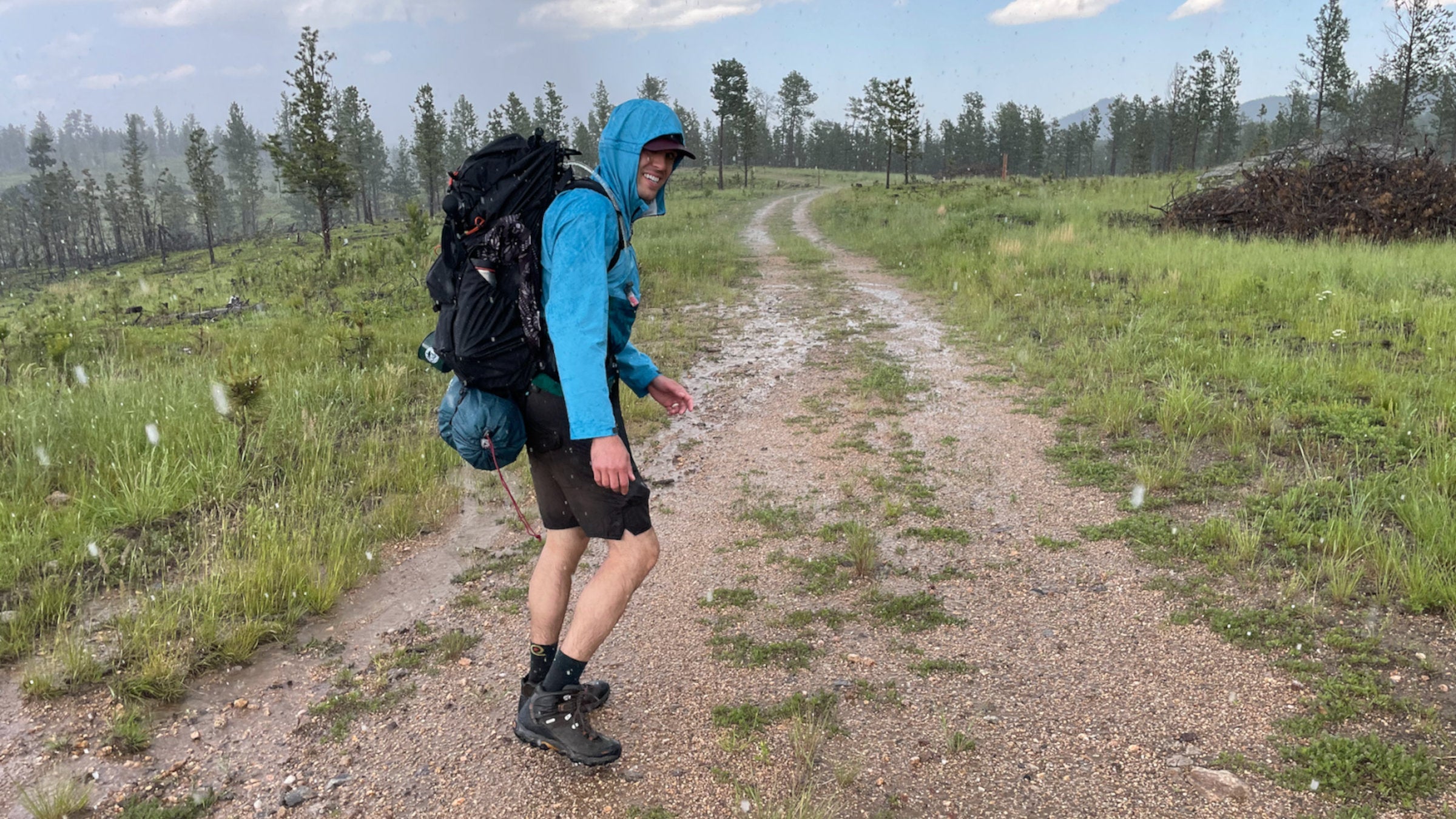 Hiker in blue raincoat smiles while hiking through the rain