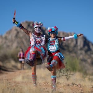 two trail runners in the desert with red and blue costumes.