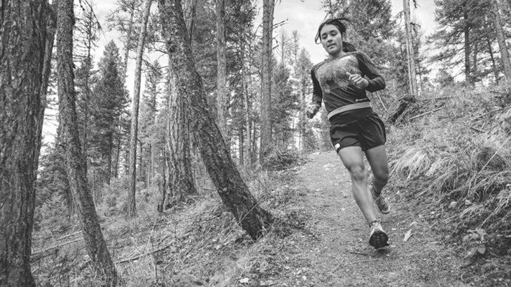 A woman runs a trail in the forest in Montana