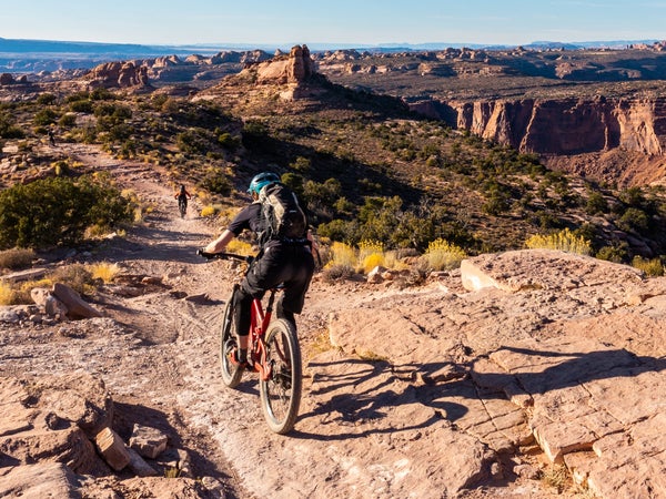 A mountain biking pedaling across single track in the Moab desert of Utah