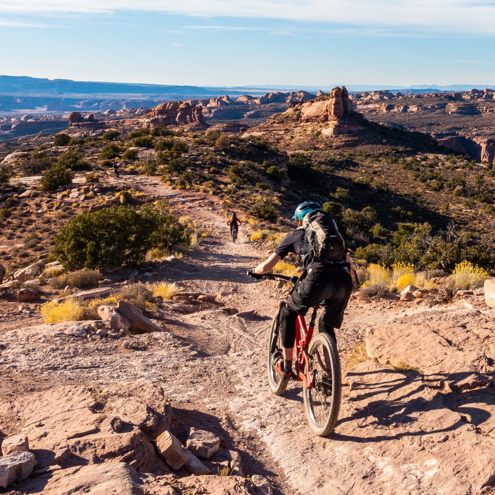 Two mountain bikers headed across single track in the desert surrounding Moab, Utah