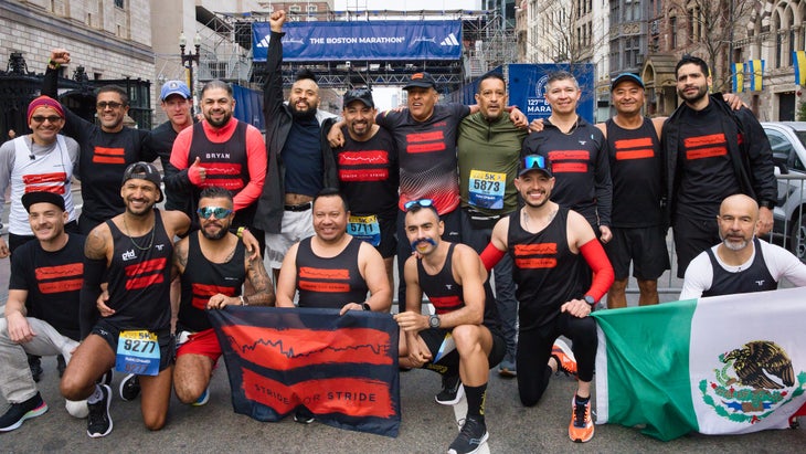 A group of runners in black pose in front of the Boston Marathon finish