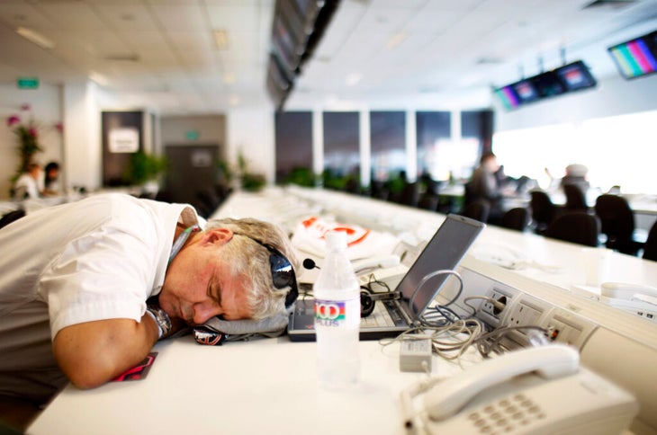 A male journalist has fallen asleep at his work desk in the middle of the day