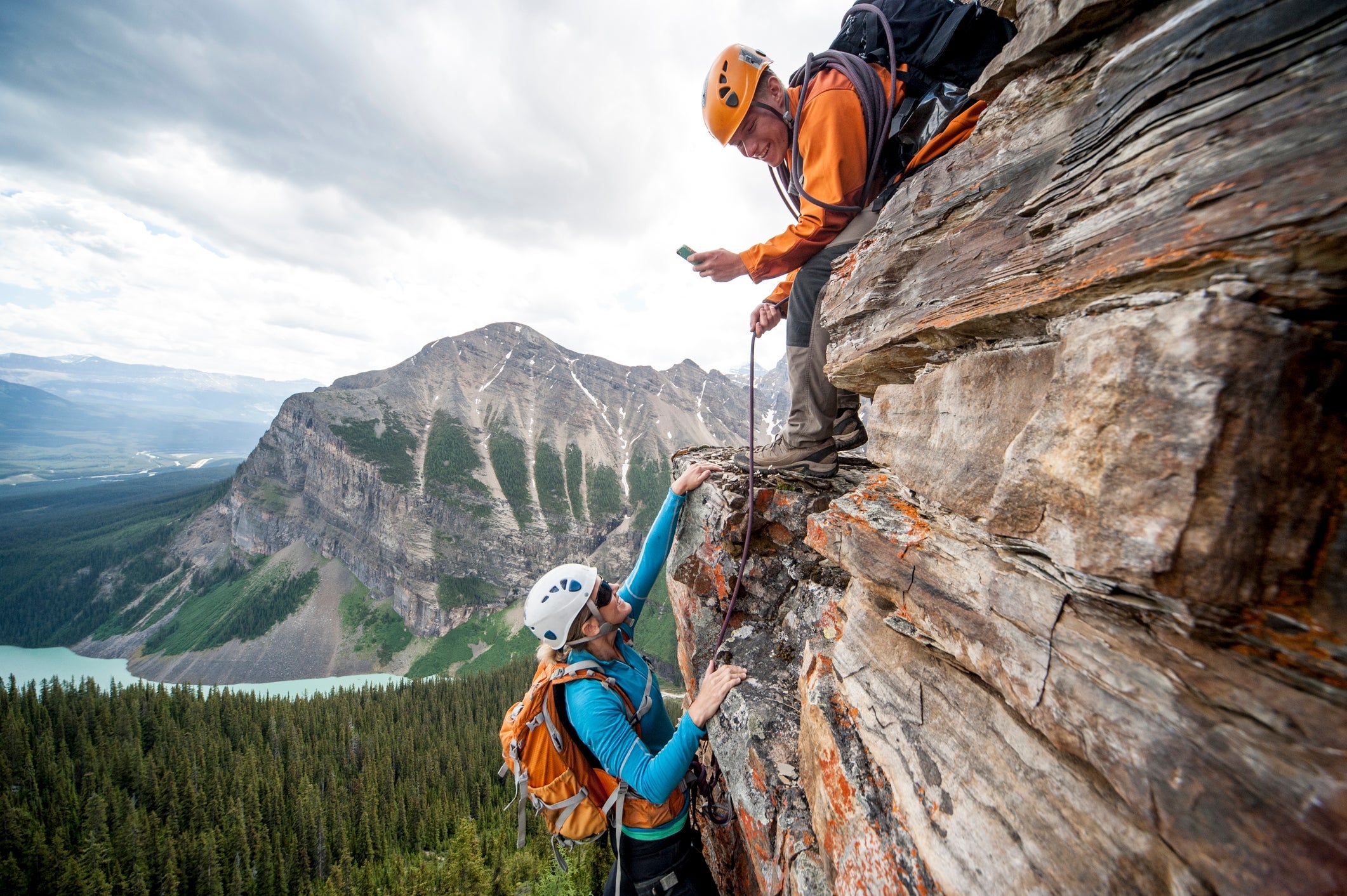 Climber takes picture of teammate ascending cliff