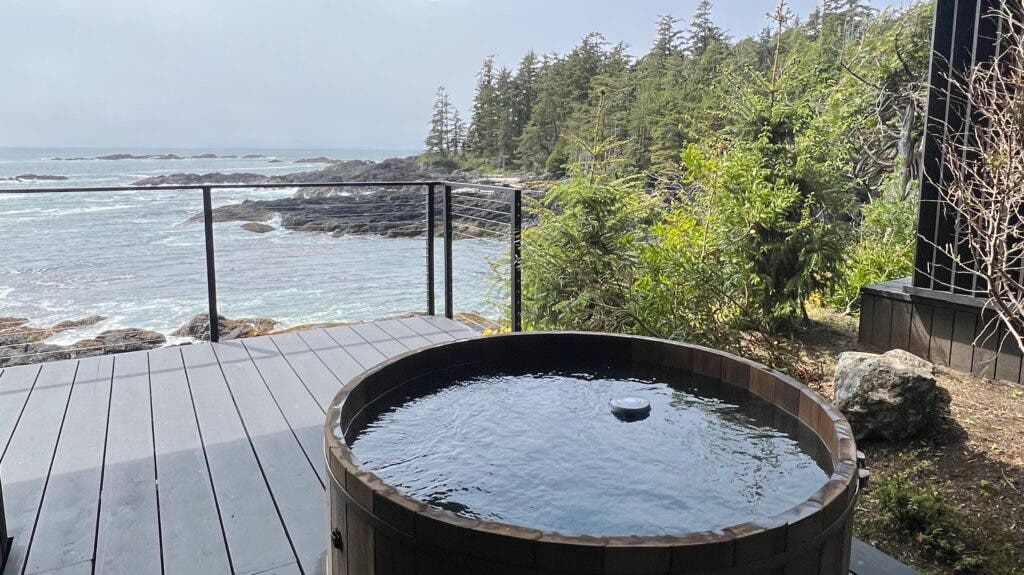A hot tub overlooks the forested coastline and ocean