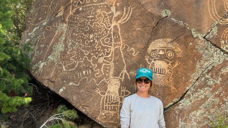 The author standing in front of a huge rock inscribed with petroglyphs