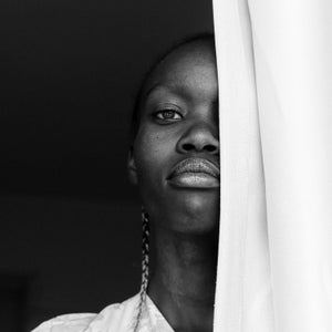 A woman looks through a curtain