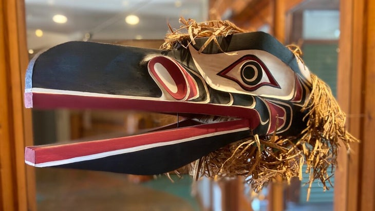 A beautiful carving of a raven head, made into a mask by a Native artist, on display in a gallery window