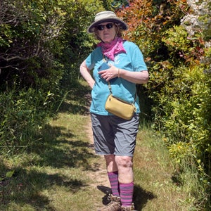 A woman standing among trees and wearing a brightly colored hiking outfit