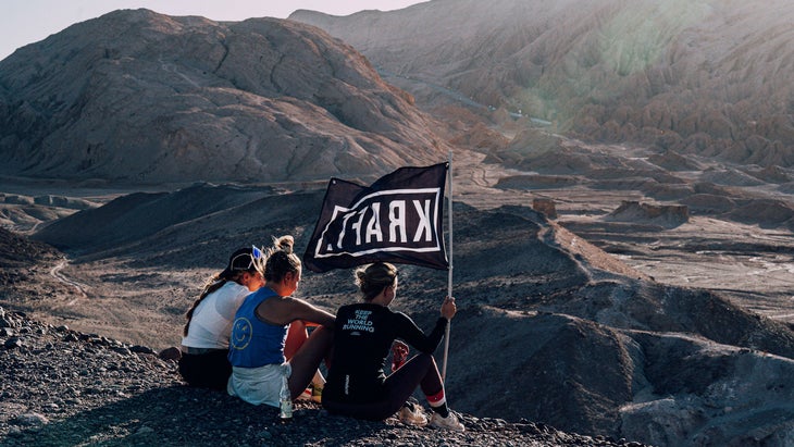 Runners sit with a black flag on a hill after running through the desert.