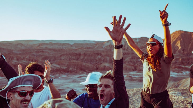 Runners celebrate at sunset after finishing the race in the desert