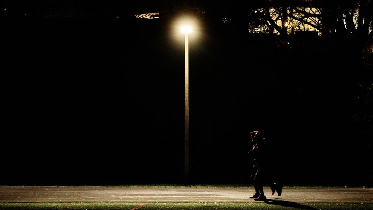 A single person runs on a track in the middle of the night. 