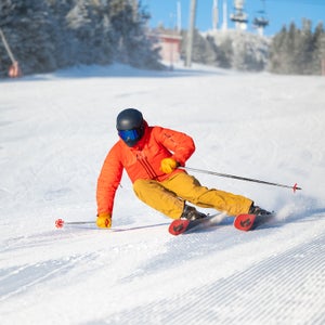 Skier wearing orange jacket carving on new Nordica Enforcer all-mountain ski.