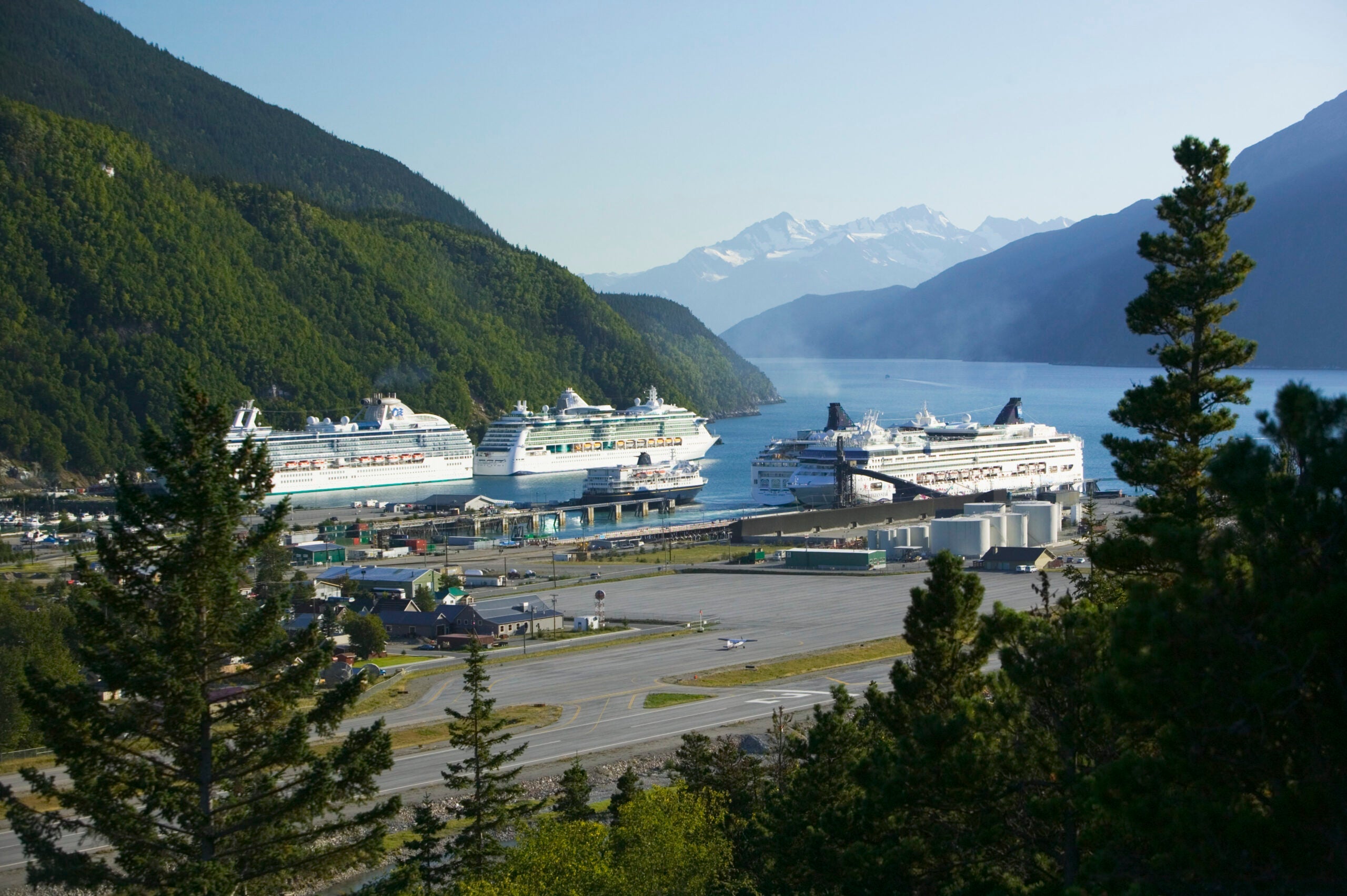 Cruise ships anchored in a port with mountains behind.