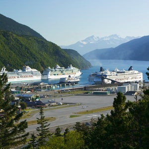 Cruise ships anchored in a port with mountains behind.