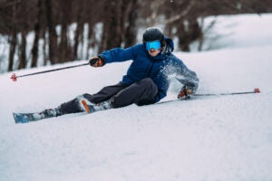 Skier wearing blue jacket carving on new Nordica Enforcer all-mountain ski. 