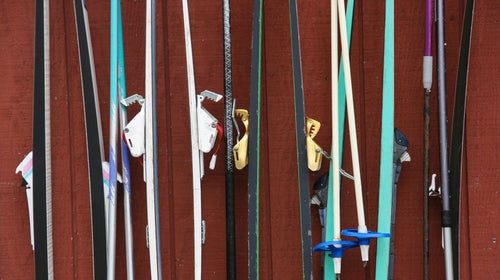Closeup of old Nordic skis hanging on rack against red backdrop
