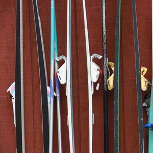 Closeup of old Nordic skis hanging off rack against red backdrop